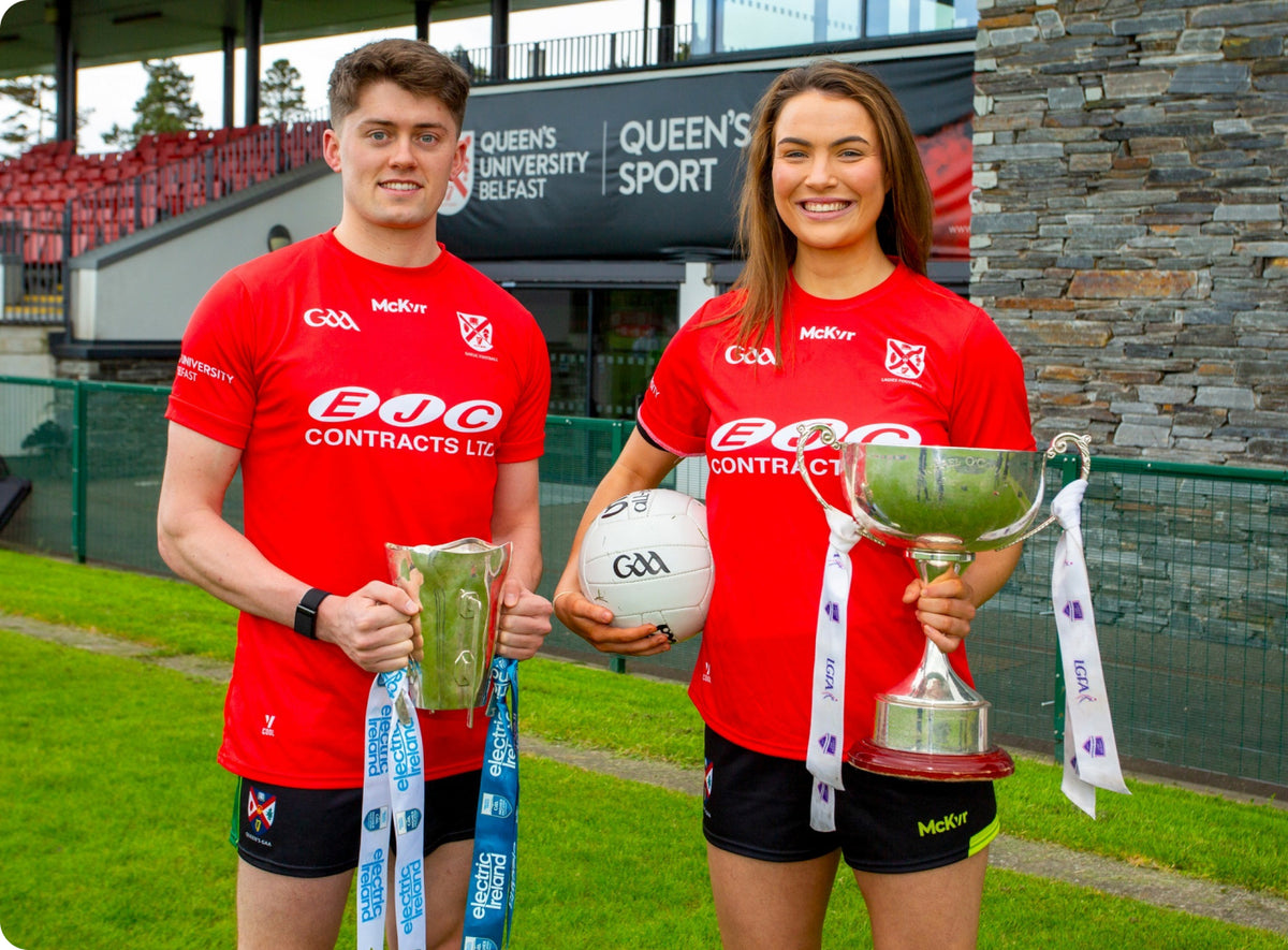 Queen's University Belfast players holding trophies in red McKvr kit